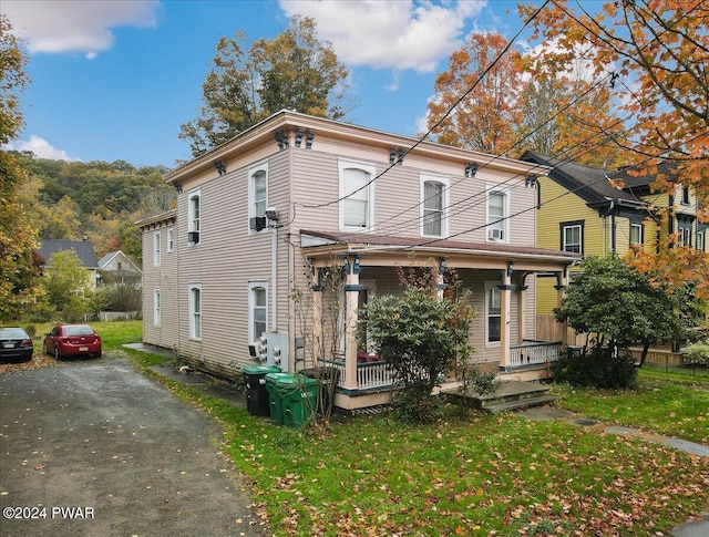 italianate house featuring covered porch and a front yard