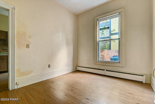 unfurnished room with light wood-type flooring and baseboard heating