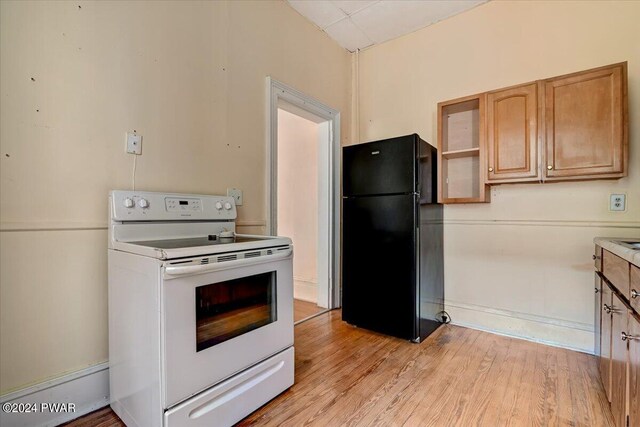 kitchen featuring black fridge, light hardwood / wood-style flooring, and white electric stove