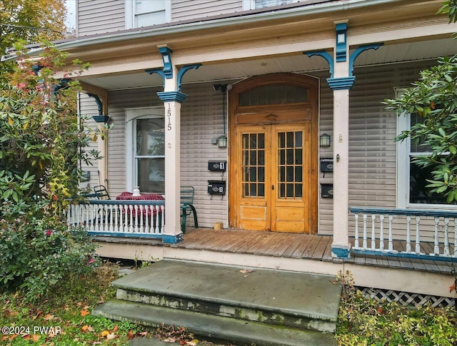 view of exterior entry featuring covered porch and french doors