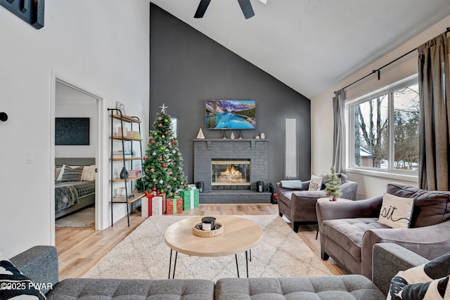 living room featuring hardwood / wood-style flooring, a brick fireplace, lofted ceiling, and ceiling fan