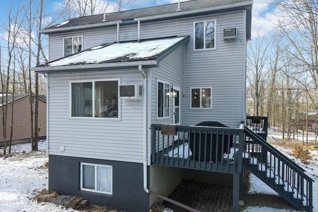 snow covered house featuring a deck and a wall unit AC