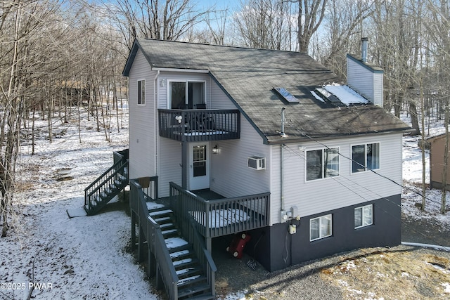 snow covered property featuring a balcony and a wall mounted air conditioner