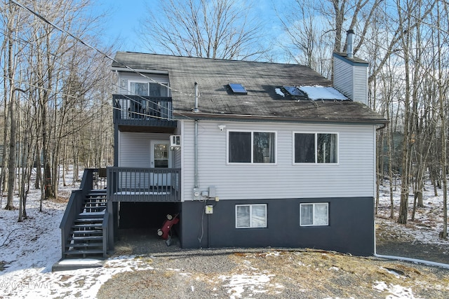 snow covered property with a wooden deck and a balcony