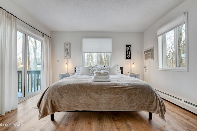 bedroom featuring access to outside, a wall mounted AC, baseboard heating, and a textured ceiling