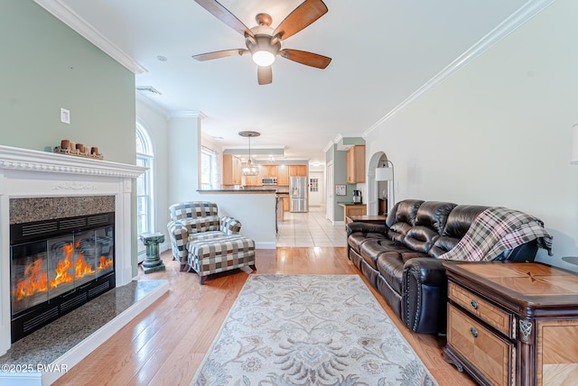302 Oneida Way, Milford, PA 18337 - living room with crown molding, ceiling fan, light wood-style floors, a premium fireplace, and arched walkways