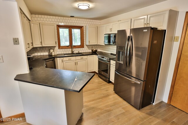 216 Canterbrook Dr, Lords Valley, PA 18328 - kitchen with appliances with stainless steel finishes, dark countertops, a peninsula, light wood-type flooring, and decorative backsplash