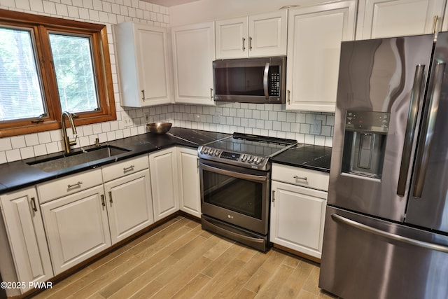 216 Canterbrook Dr, Lords Valley, PA 18328 - kitchen with stainless steel appliances, white cabinetry, light wood-type flooring, tasteful backsplash, and dark countertops