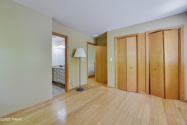 2766 Owego Tpke, Hawley, PA 18428 - unfurnished bedroom with wood finished floors, multiple closets, ensuite bathroom, a sink, and baseboards
