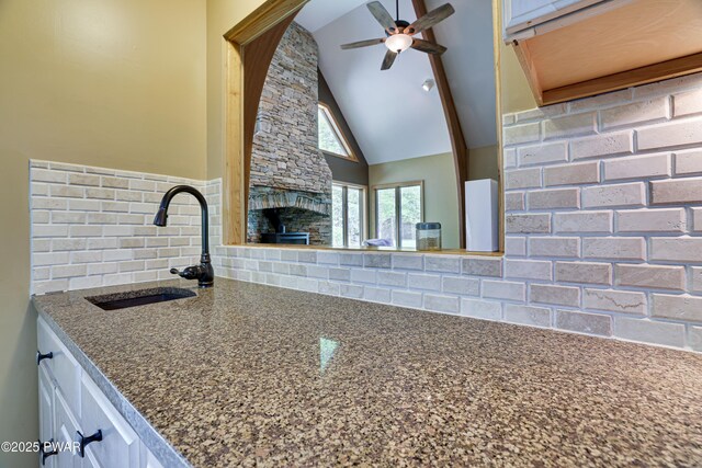 2766 Owego Tpke, Hawley, PA 18428 - kitchen featuring backsplash, a sink, a fireplace, a ceiling fan, and dark stone countertops