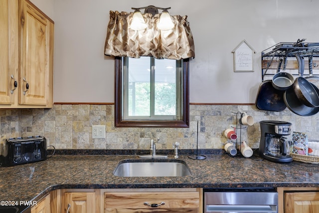 kitchen with dark stone countertops, sink, and light brown cabinetry