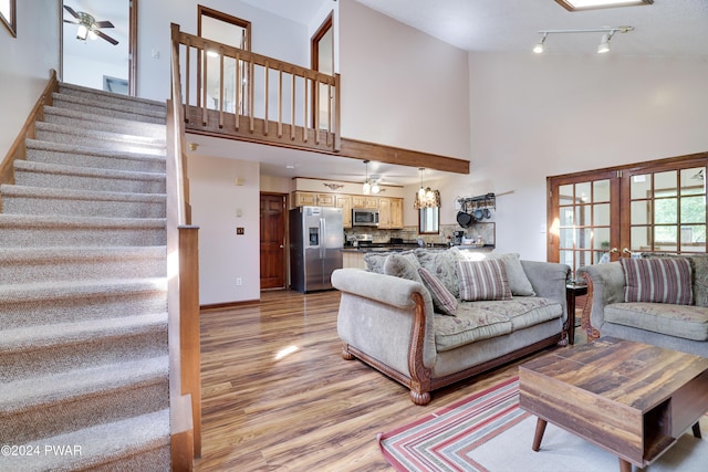 living room featuring a high ceiling, light hardwood / wood-style flooring, and ceiling fan