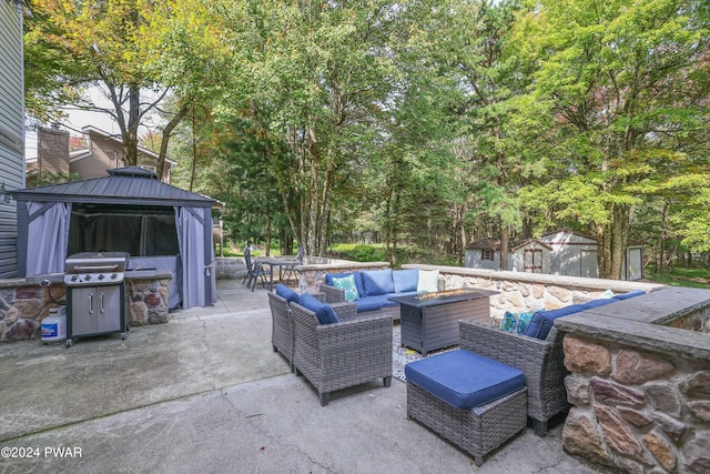 view of patio / terrace with a gazebo, a shed, grilling area, and an outdoor living space with a fire pit