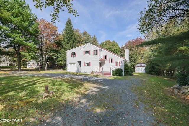 view of front of house with a storage unit, a garage, and a front yard