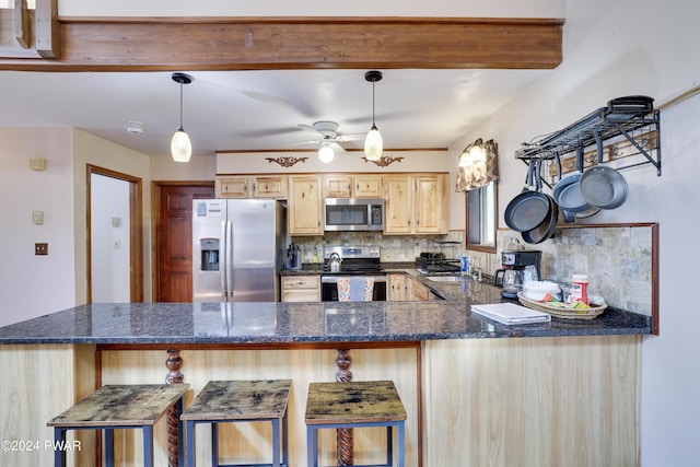 kitchen with decorative backsplash, appliances with stainless steel finishes, hanging light fixtures, and light brown cabinetry