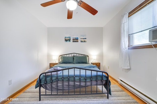 bedroom with baseboard heating, ceiling fan, and hardwood / wood-style flooring