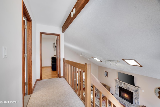 corridor with a textured ceiling, light colored carpet, and lofted ceiling