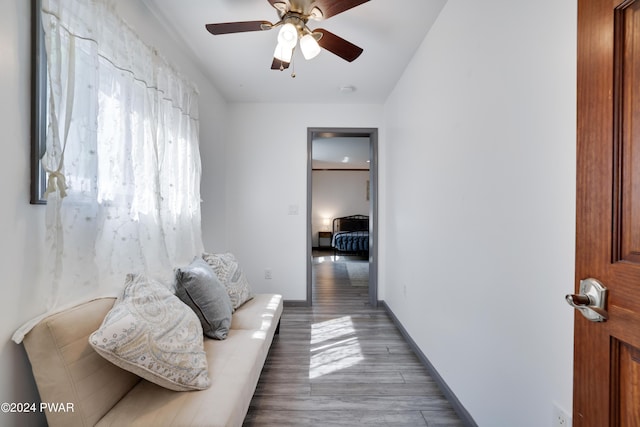 sitting room with ceiling fan and wood-type flooring