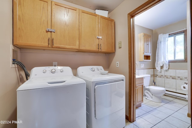 clothes washing area featuring light tile patterned floors, a baseboard radiator, washer and clothes dryer, and tile walls