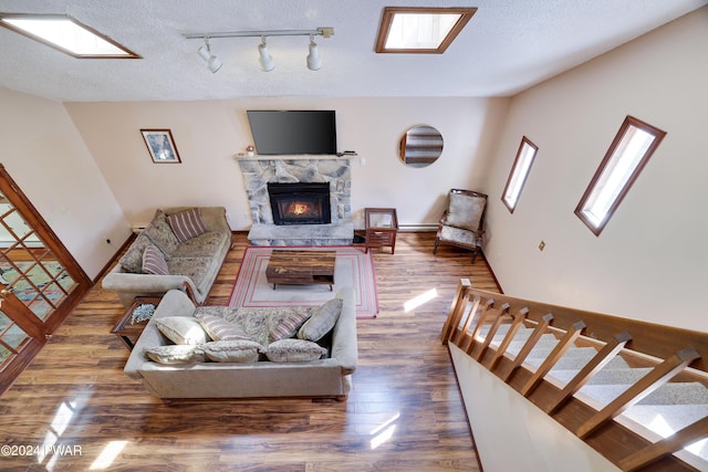 living room with a stone fireplace, hardwood / wood-style floors, and a textured ceiling