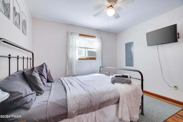 bedroom with cooling unit, electric panel, ceiling fan, and hardwood / wood-style flooring