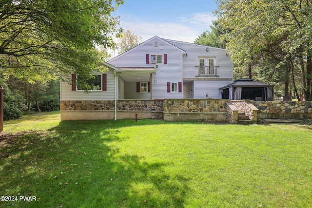 rear view of property with a lawn, a balcony, and a gazebo