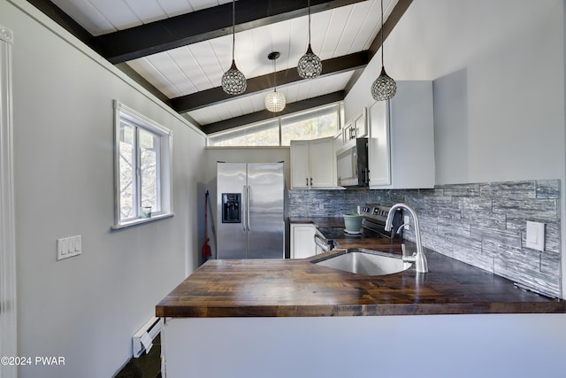 kitchen with wood counters, white cabinets, hanging light fixtures, vaulted ceiling with beams, and stainless steel appliances