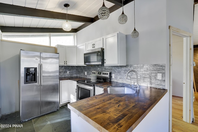 kitchen with appliances with stainless steel finishes, sink, beam ceiling, butcher block countertops, and hanging light fixtures