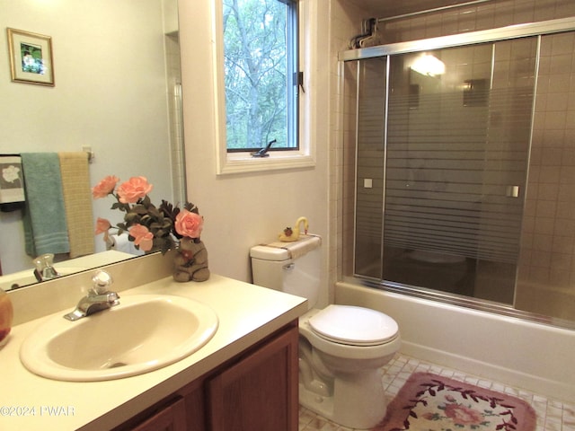 full bathroom featuring combined bath / shower with glass door, tile patterned floors, vanity, and toilet