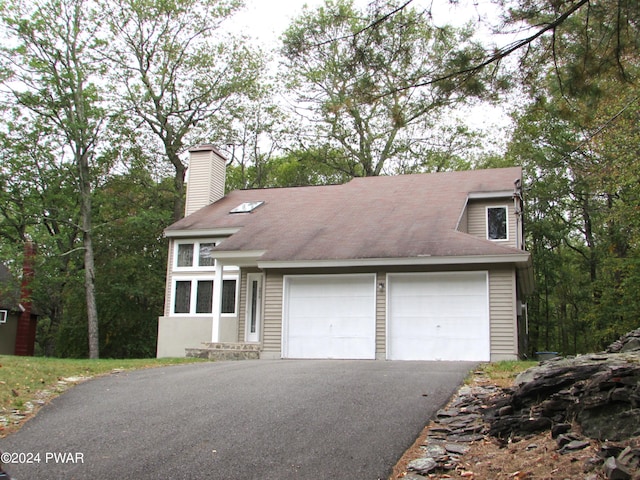 view of front of house featuring aphalt driveway, a chimney, and an attached garage