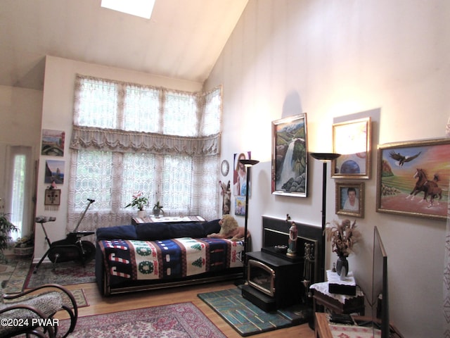 living room with a wood stove, high vaulted ceiling, a skylight, and wood-type flooring