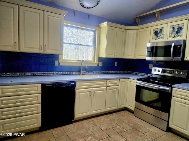 kitchen with appliances with stainless steel finishes, tasteful backsplash, vaulted ceiling, cream cabinets, and sink