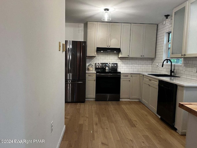 kitchen with black appliances, sink, decorative backsplash, light wood-type flooring, and butcher block counters