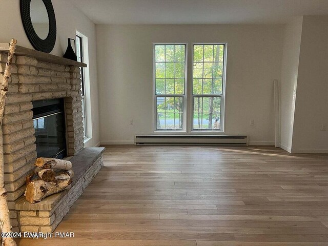 unfurnished living room with a fireplace, a baseboard radiator, and light wood-type flooring