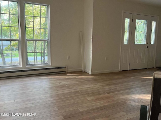 foyer entrance featuring light hardwood / wood-style flooring, baseboard heating, and a healthy amount of sunlight