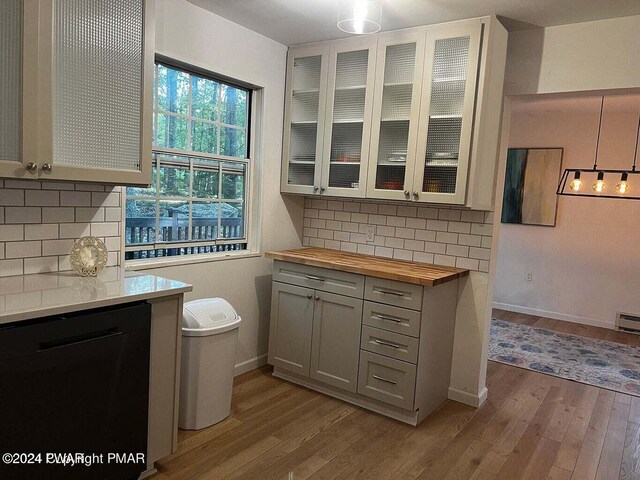 kitchen featuring dishwasher, decorative backsplash, butcher block countertops, and light hardwood / wood-style flooring