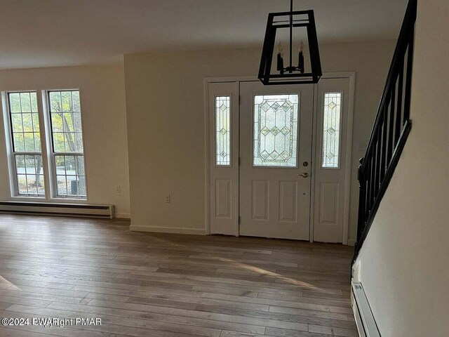 foyer with wood-type flooring, a chandelier, and a baseboard heating unit