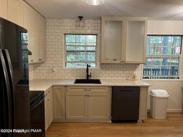 kitchen featuring decorative backsplash, sink, black appliances, and plenty of natural light