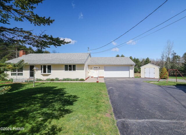 single story home with a storage unit, a garage, and a front lawn