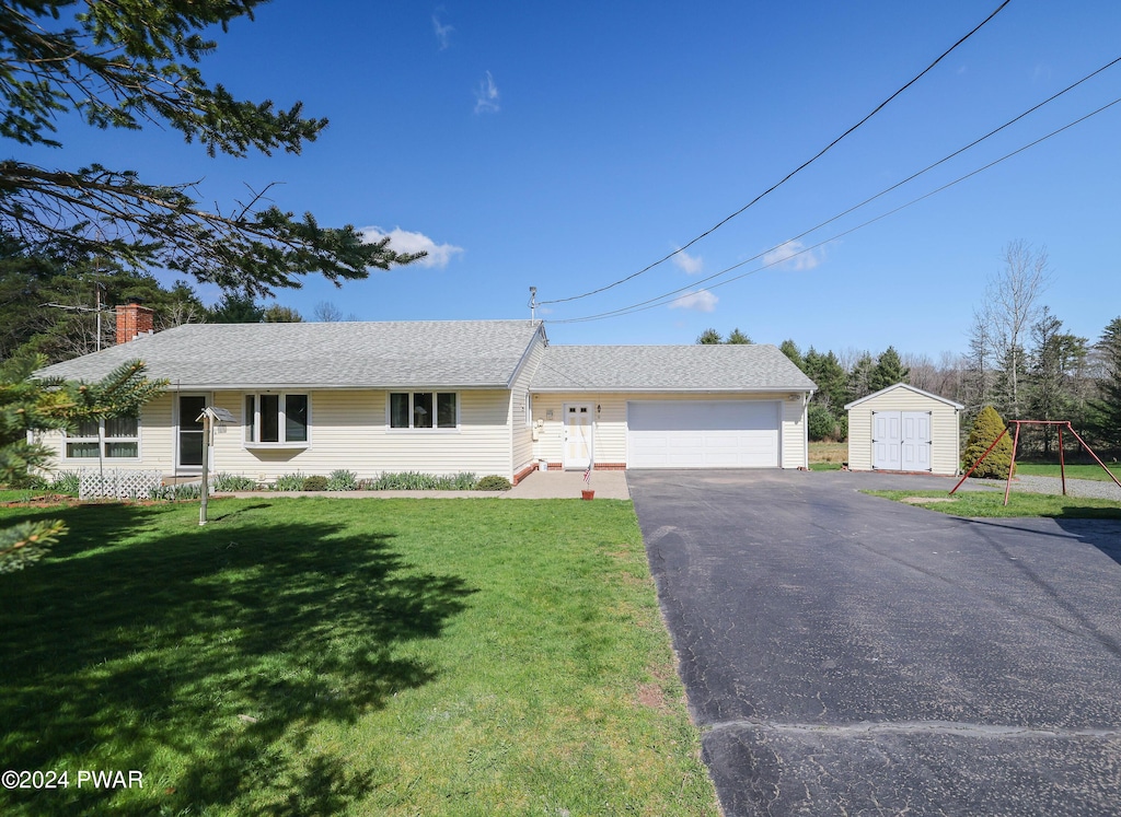 single story home with a storage unit, a garage, and a front lawn