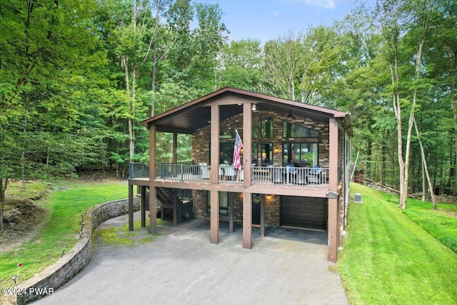 49 White Pine Cir, Lake Ariel, PA 18436 - view of front of home with stone siding, driveway, a front lawn, an attached garage, and a wooden deck