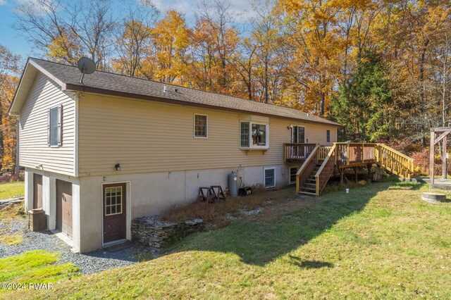 back of house with a garage, a lawn, and a wooden deck