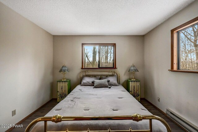 bedroom featuring multiple windows, baseboard heating, and dark wood-style floors