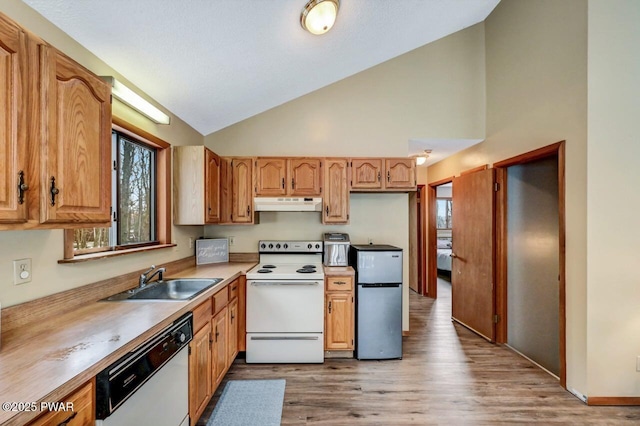 kitchen with a sink, under cabinet range hood, white appliances, light wood-style floors, and lofted ceiling