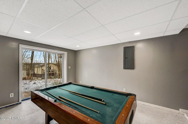 recreation room featuring electric panel, a drop ceiling, baseboards, and recessed lighting