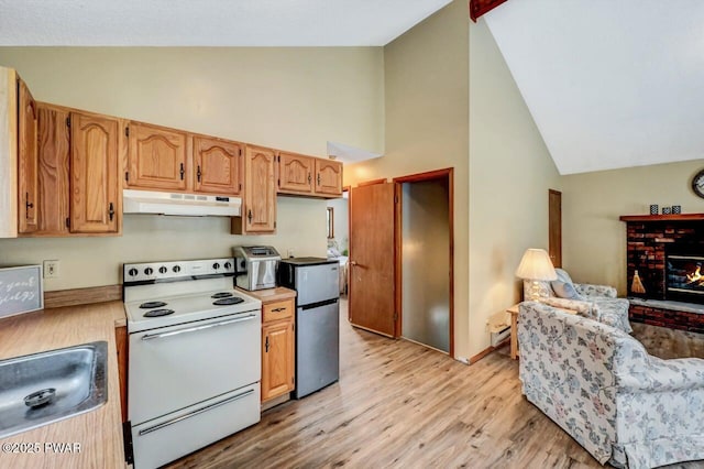 kitchen featuring light wood-style flooring, under cabinet range hood, a sink, white electric range oven, and freestanding refrigerator