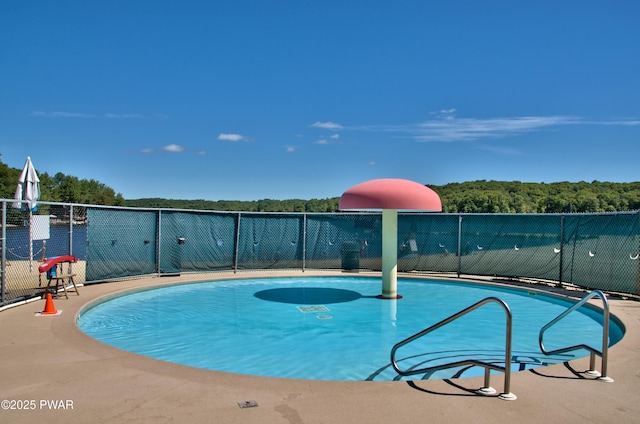 view of swimming pool with a forest view, a fenced in pool, and fence