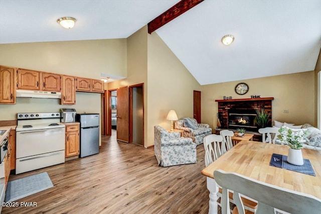 kitchen with light wood-style flooring, electric stove, under cabinet range hood, freestanding refrigerator, and a fireplace