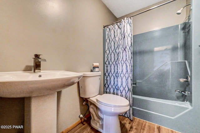 full bath with toilet, wood finished floors, and shower / tub combo with curtain