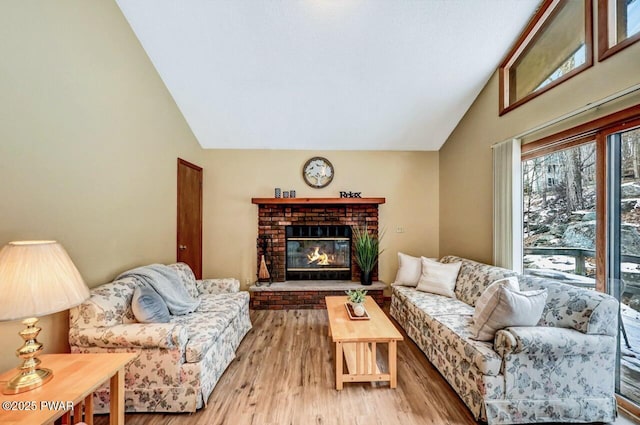 living area with vaulted ceiling, light wood-style flooring, and a fireplace